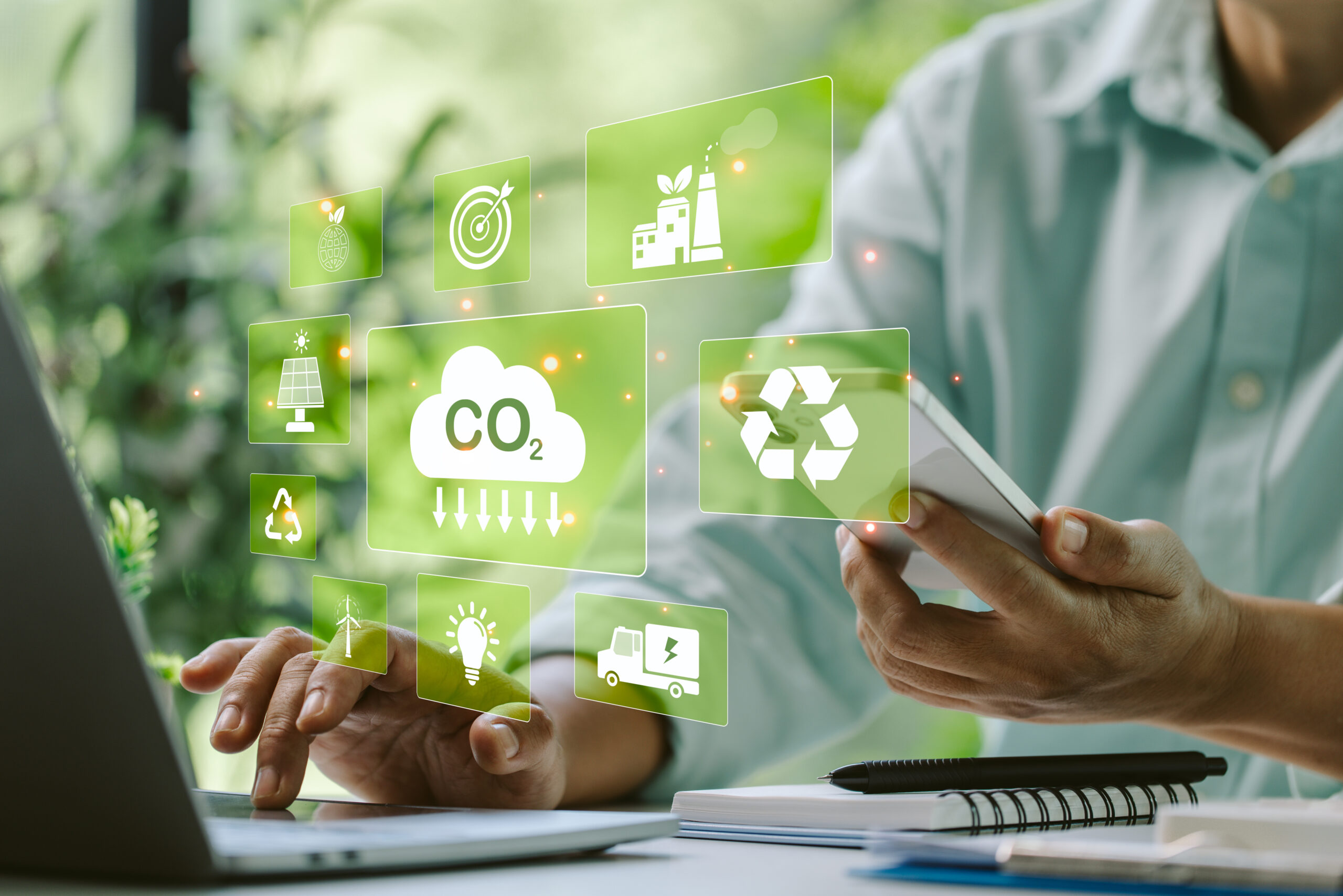 Digital tools and CO2 reduction icons displayed over a business professional working on a laptop.